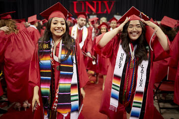 two women in graduation gowns with &quot;UNLV Latinx&quot; Stolls